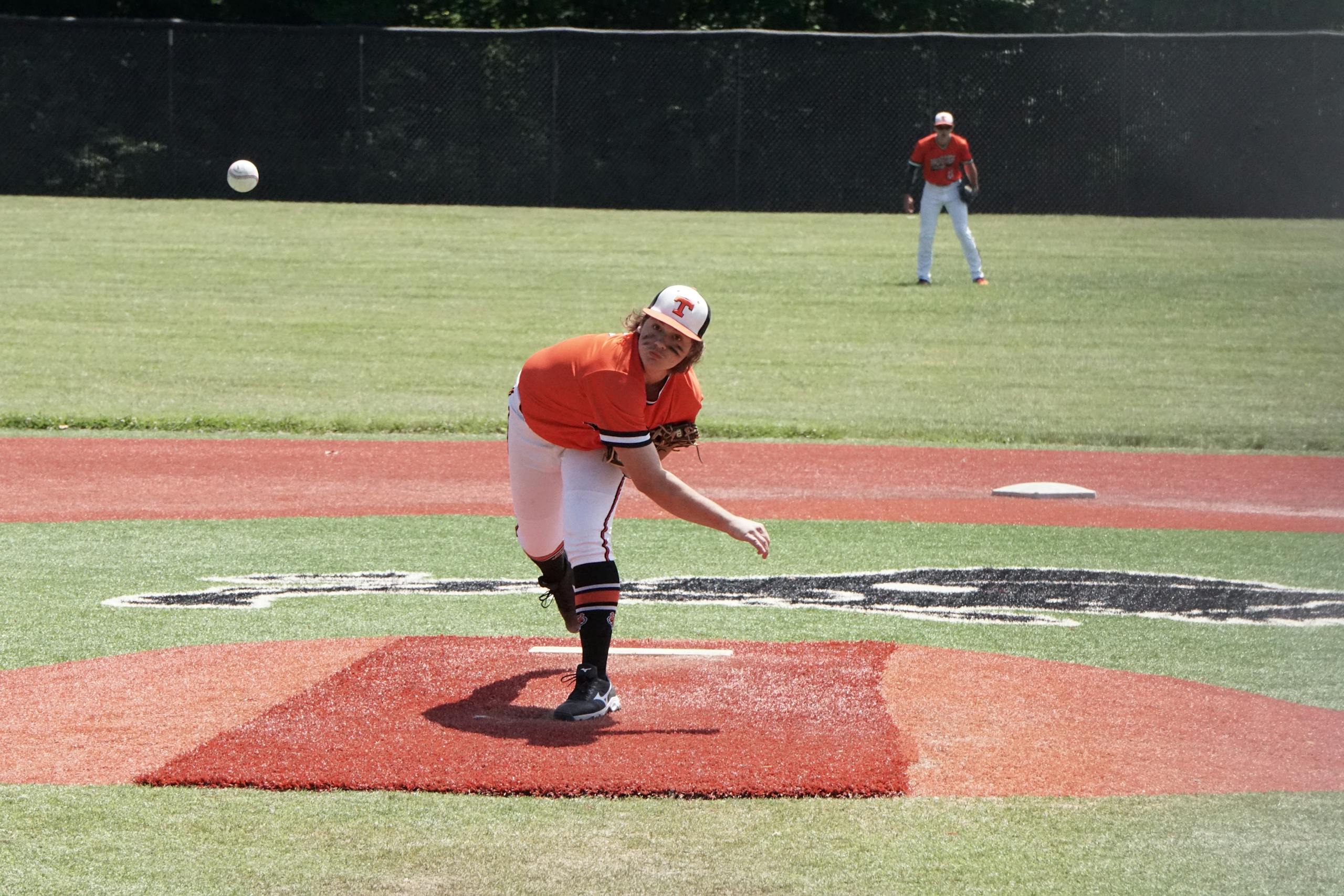 Young baseball pitcher throwing a pitch during a game on an outdoor field.